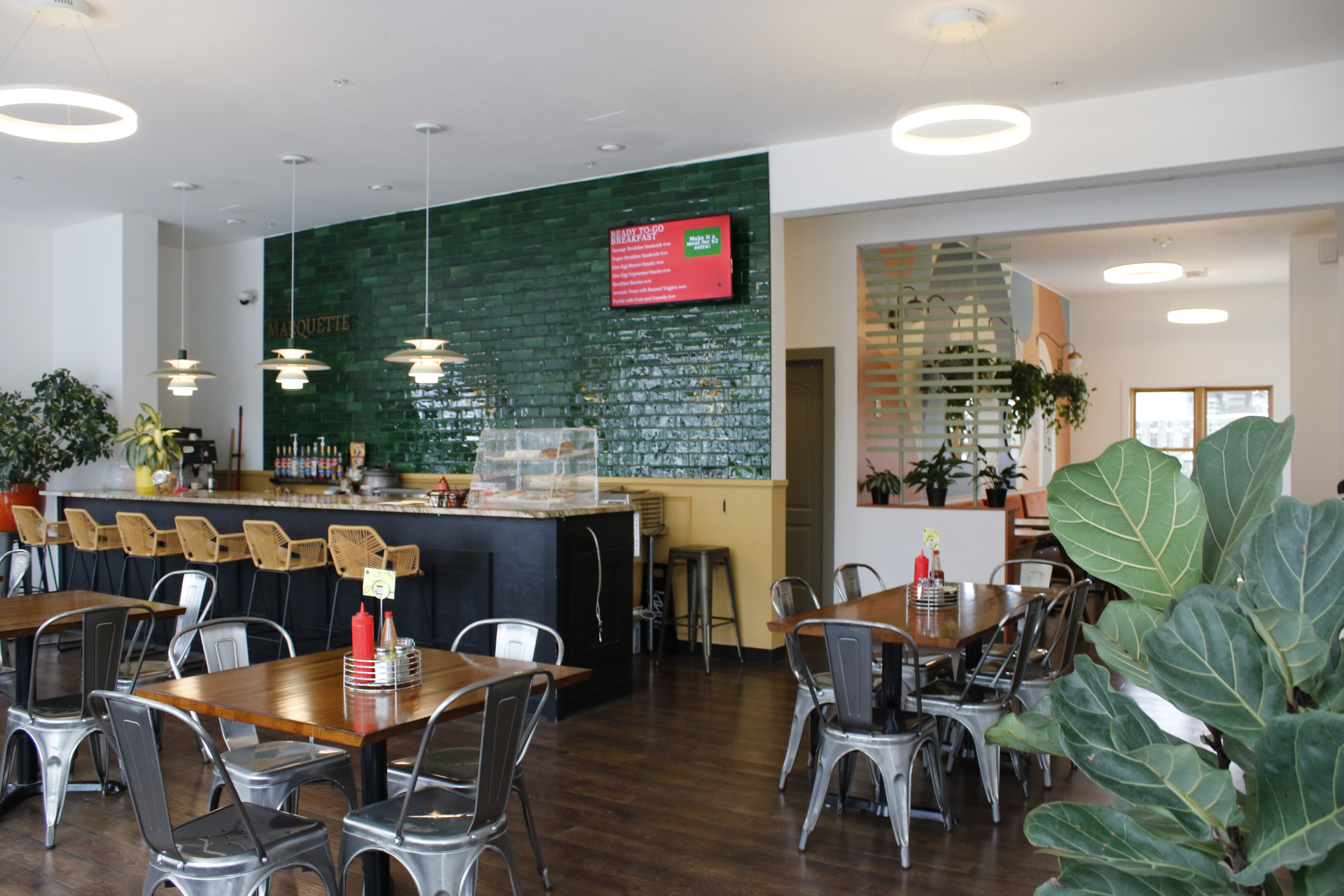 The Marquette cafe with emerald tile bar and warm wood tables